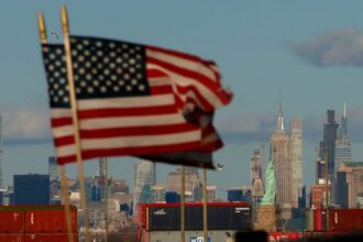 BAYONNE, NJ - FEBRUARY 1: Shipping containers stand on a dock at the Port Jersey container terminal in front of the Statue of Liberty and the Empire State Building in New York City on February 1, 2025, as seen from Bayonne, New Jersey.  (Photo by Gary Hershorn/Getty Images)