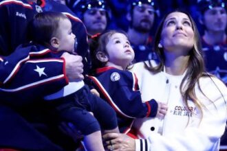 COLUMBUS, OHIO - OCTOBER 15:  Sean Monahan #23 of the Columbus Blue Jackets stands on the ice while holding former Columbus Blue Jackets player Johnny Gaudreaus son, Johnny Jr, along side Gaudreaus wife and daughter, Meredith and Noah, and his brother-in-law Eddie Morris, during a remembrance ceremony prior to the start of the game against the Florida Panthers at Nationwide Arena on October 15, 2024 in Columbus, Ohio. Gaudreau and his brother Matthew were killed when hit by a suspected drunk driver on August 29, 2024.(Photo by Kirk Irwin/NHLI via Getty Images)