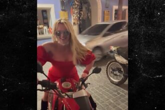 Britney Spears salta sul retro della moto in abito rosso brillante