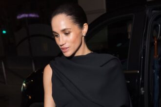 Meghan Markle indossa un elegante abito nero con un mantello durante la settimana della moda di Parigi