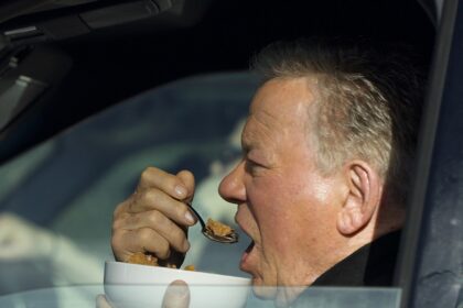 William Shatner fotografato mentre mangiava una ciotola di cereali nella sua auto al semaforo